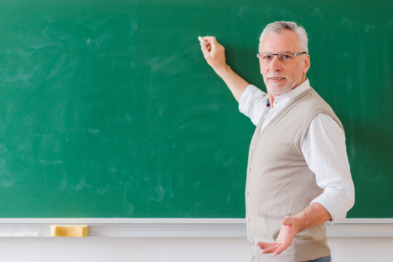 professor masculino senior explicando e escrevendo na lousa verde